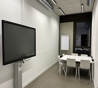 6 Stühle um zwei Tische, ein Flipchart, ein Smartboard