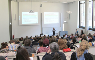 Voller Hörsaal mit Dozentin vorne