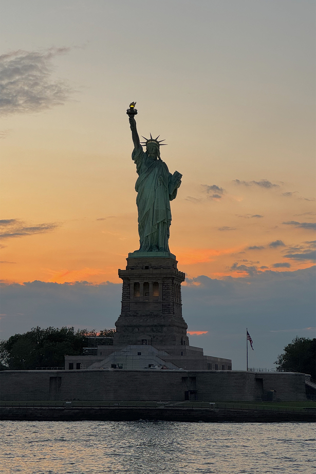 Die freiheitsstatue in New York vor einem orangen Sonnenuntergang