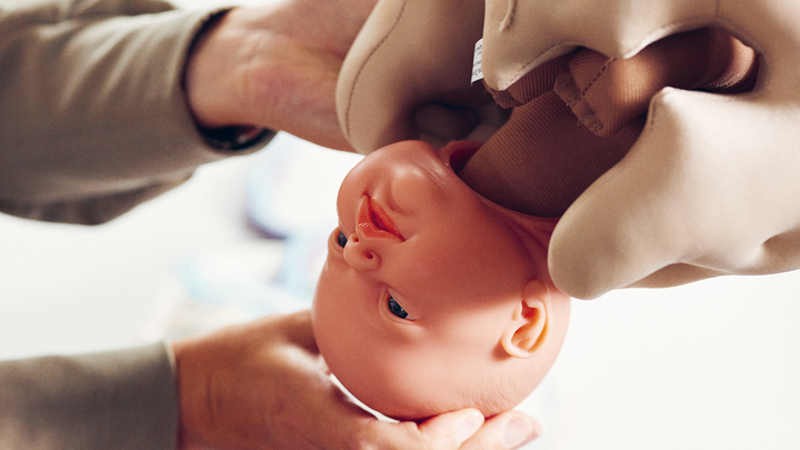 studierende halten eine Baby Puppe in der Hand